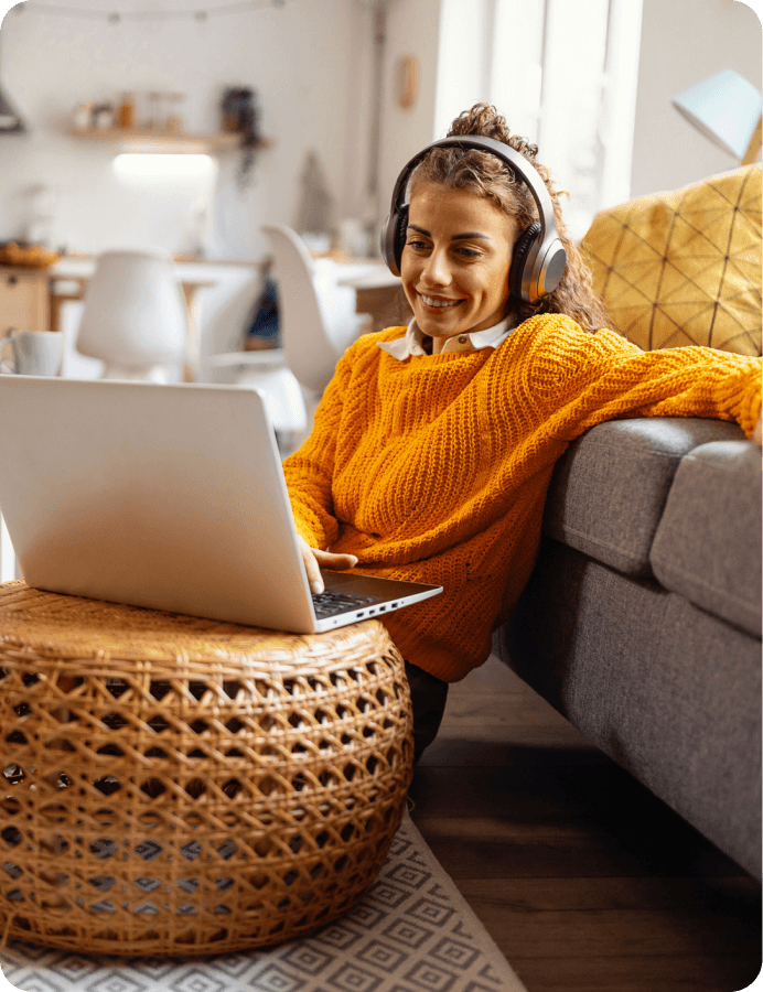 a woman smiling while listening to something on the laptop via her headphone